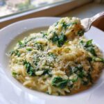 A fork lifts a cheesy bite of Creamy Garlic Parmesan Orzo with Spinach, showing melted cheese strings.
