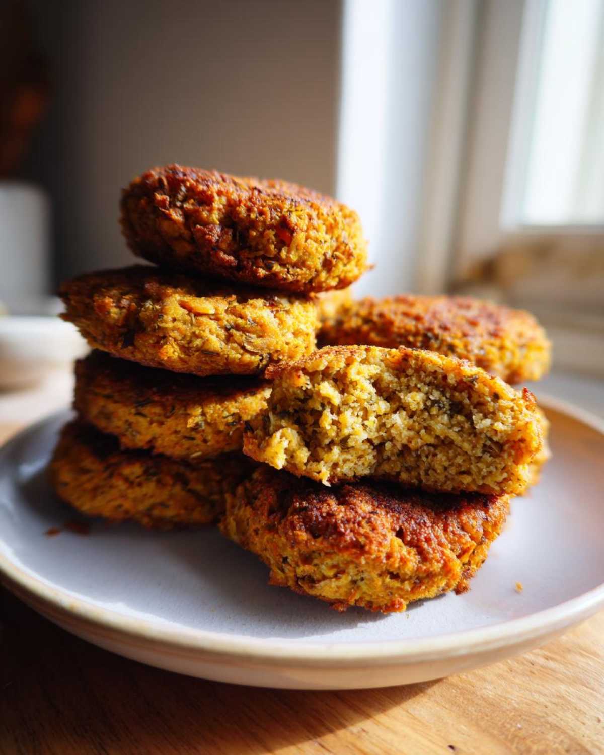 A stack of golden brown, crispy air fryer falafel, with one broken open to show the texture inside.