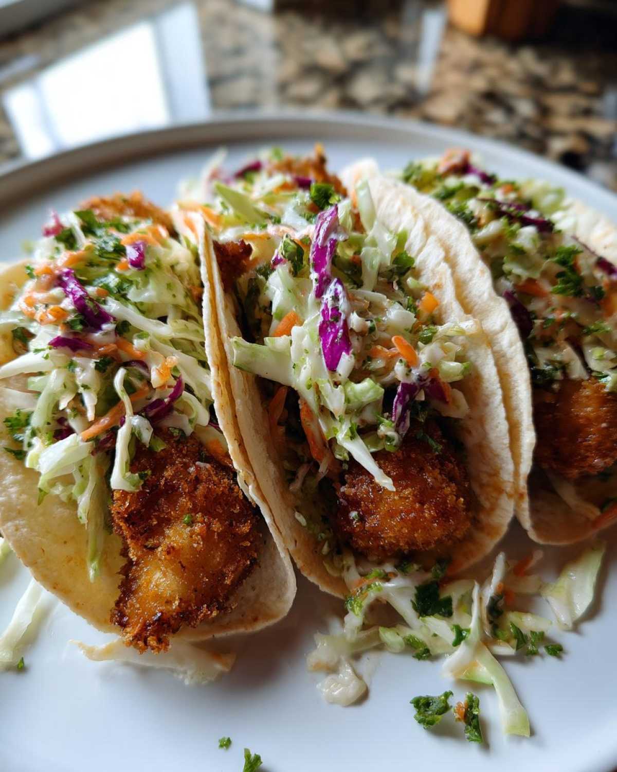 Three Crispy Baked Fish Tacos filled with golden fried fish and topped generously with bright lime slaw.