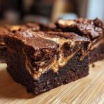 Close-up of a fudgy Dark Chocolate Tahini Brownies square with a visible tahini swirl on a wooden cutting board.