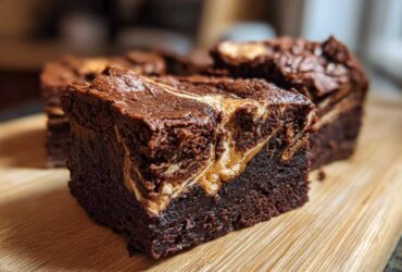 Close-up of a fudgy Dark Chocolate Tahini Brownies square with a visible tahini swirl on a wooden cutting board.