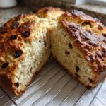 Close-up of Easy Irish Soda Bread with Buttermilk and Raisins, cut in half on a cooling rack.