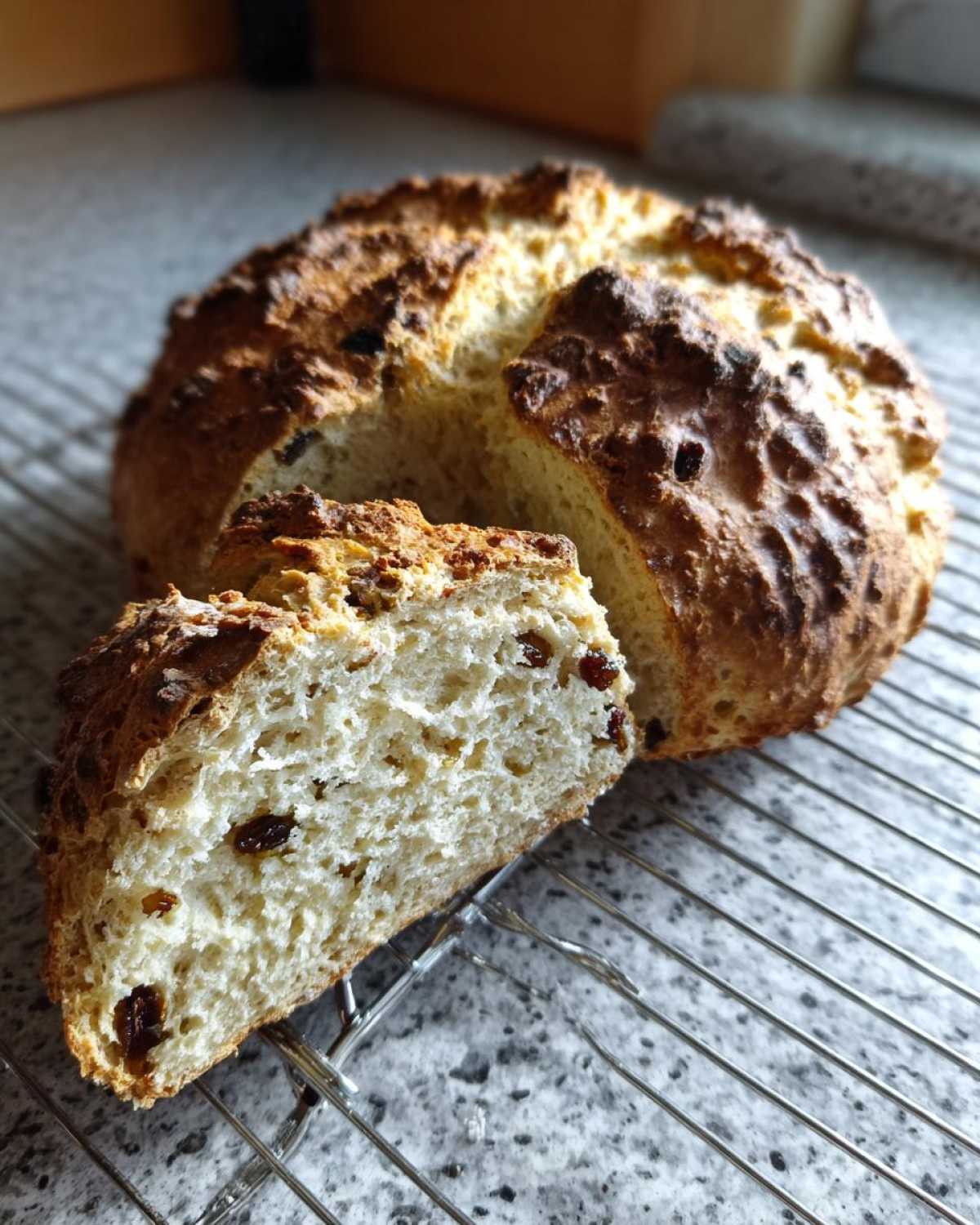 A freshly baked loaf of Easy Irish Soda Bread with Buttermilk and Raisins, sliced open to show the soft interior.