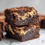 Two fudgy Dark Chocolate Tahini Brownies stacked, showing the rich dark interior and the light tahini swirl.