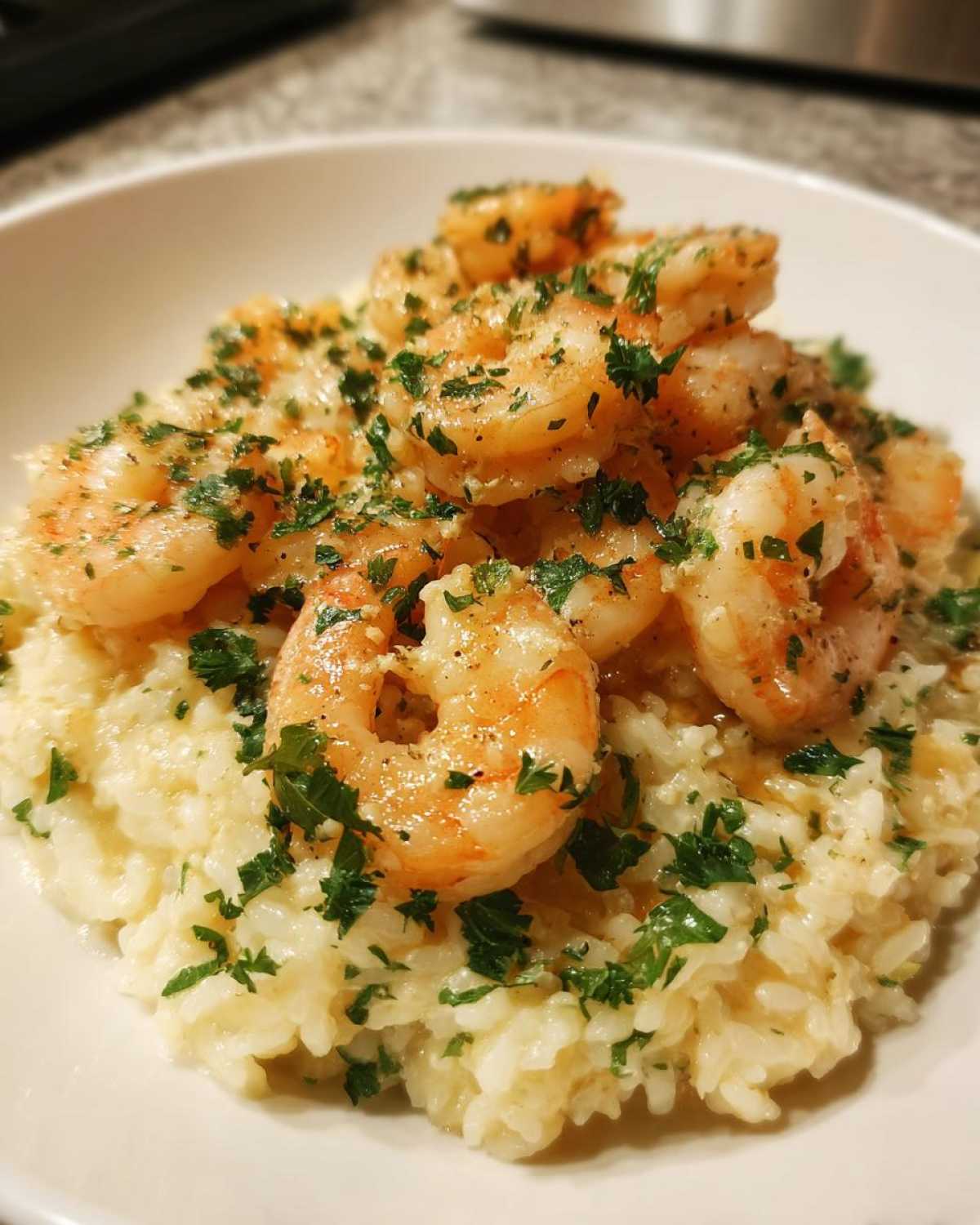 A close-up of creamy rice topped with seasoned shrimp and fresh parsley, representing Garlic Butter Shrimp and Rice Skillet.