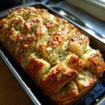 Freshly baked Garlic Parmesan Pull-Apart Bread, golden brown and cheesy, sitting in a dark baking pan.