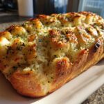 A golden-brown loaf of cheesy Garlic Parmesan Pull-Apart Bread, topped with melted cheese and herbs.