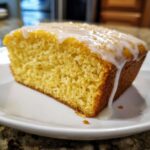 Close-up of a moist slice of Gluten-Free Lemon Coconut Cake topped with a thick white lemon glaze.
