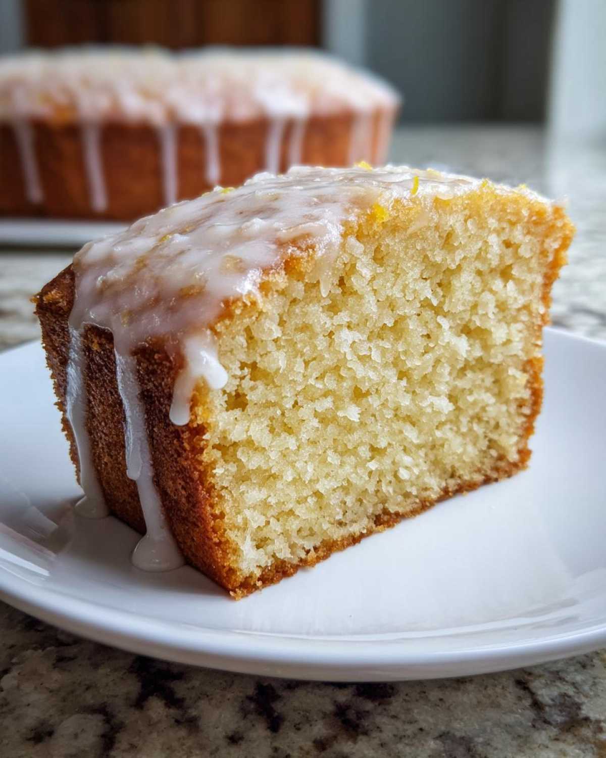 Close-up of a moist slice of Gluten-Free Lemon Coconut Cake topped with a thick white lemon glaze.