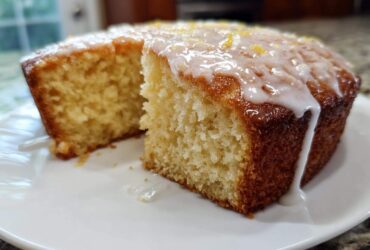 Close-up of a moist Gluten-Free Lemon Coconut Cake with white glaze dripping down the side.