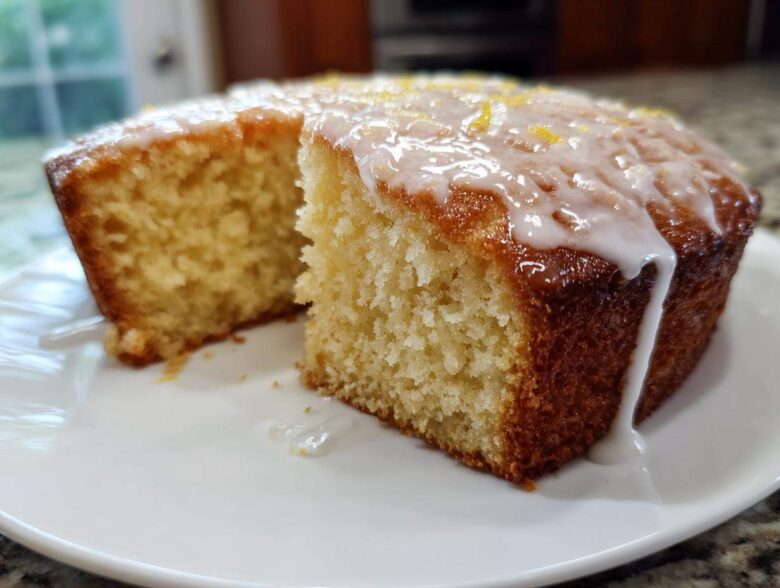 Close-up of a moist Gluten-Free Lemon Coconut Cake with white glaze dripping down the side.
