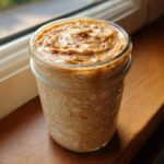 A glass jar filled with creamy High-Protein Peanut Butter Overnight Oats, topped with extra peanut butter.