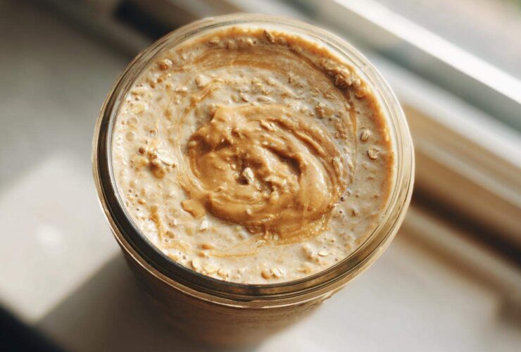 Overhead close-up of High-Protein Peanut Butter Overnight Oats topped with a swirl of peanut butter in a glass jar.