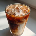 Close-up of an Iced Brown Sugar Oatmilk Latte showing swirling patterns of coffee and oat milk over ice cubes.
