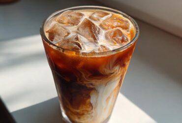 Close-up of an Iced Brown Sugar Oatmilk Latte showing swirling patterns of coffee and oat milk over ice cubes.