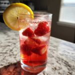 Close-up of Iced Strawberry Lemon Tea with fresh strawberries, ice, and a lemon slice garnish.