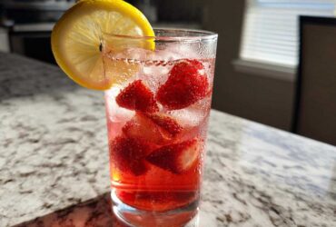 Close-up of Iced Strawberry Lemon Tea with fresh strawberries, ice, and a lemon slice garnish.