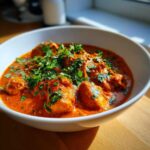A close-up of vibrant orange Instant Pot Butter Chicken topped generously with fresh cilantro.