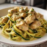 A bowl of Keto Chicken Alfredo featuring chunks of seasoned chicken over zucchini noodles tossed in a creamy sauce.