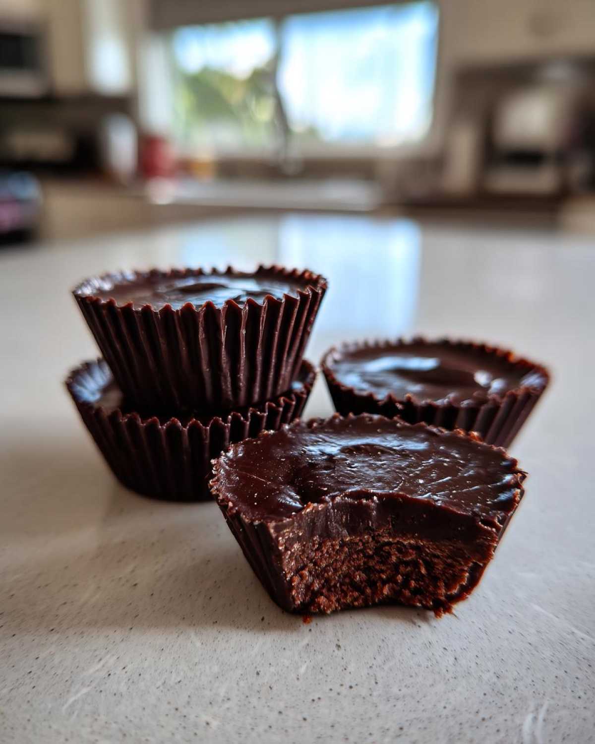 Close-up of several Keto Chocolate Peanut Butter Fat Bombs, one with a bite taken out showing the rich texture.