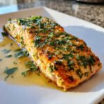 Close-up of a perfectly cooked Keto Garlic Butter Salmon fillet glistening with butter sauce and topped with fresh green herbs.