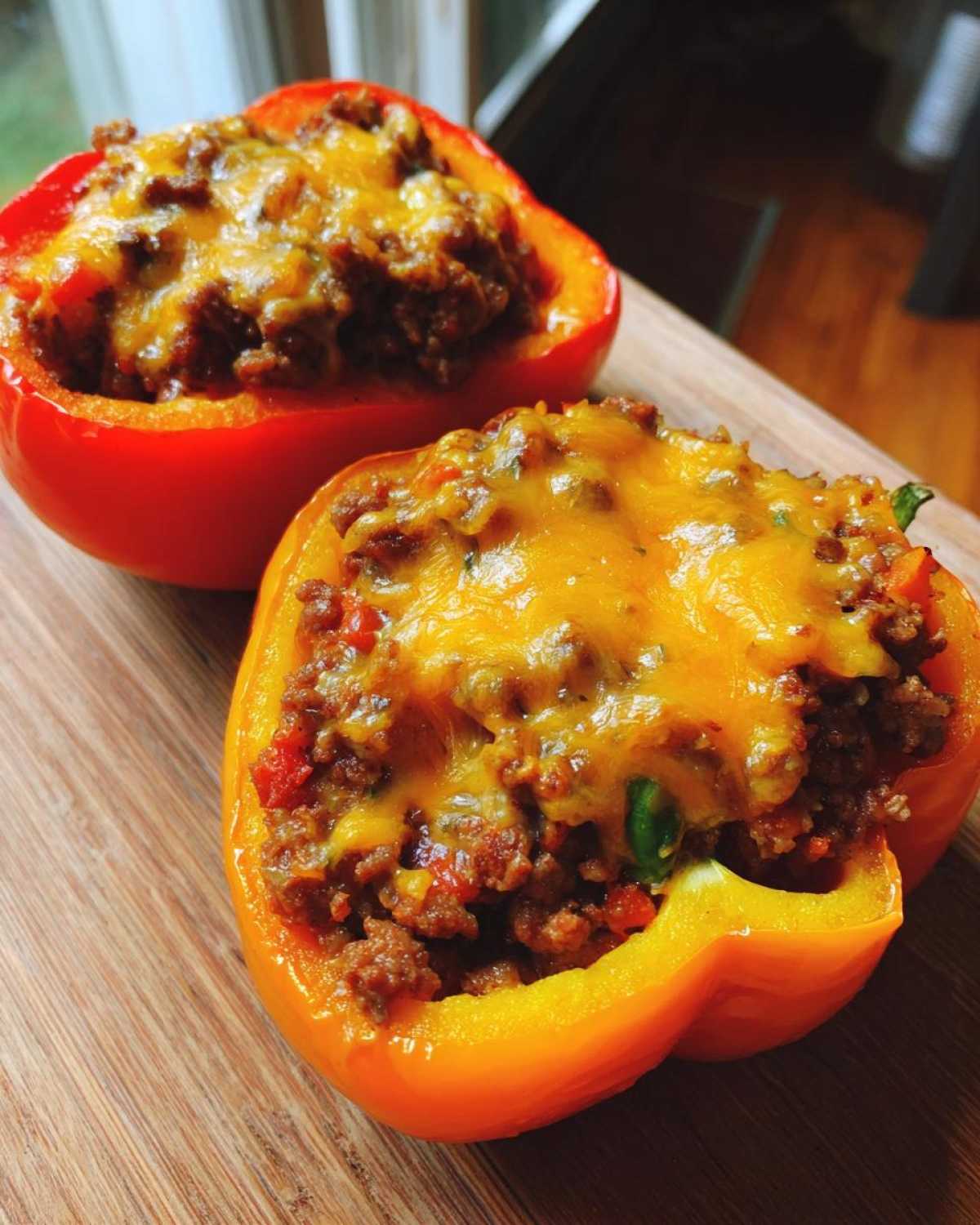 Two halves of Keto Taco Stuffed Peppers filled with seasoned ground meat and topped with melted cheddar cheese.