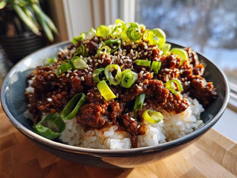 A close-up of Korean Ground Beef Bulgogi Bowls featuring seasoned ground beef over white rice, topped with sesame seeds and sliced green onions.