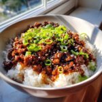 A bowl of Korean Ground Beef Bulgogi Bowls served over white rice, topped with green onions and sesame seeds.