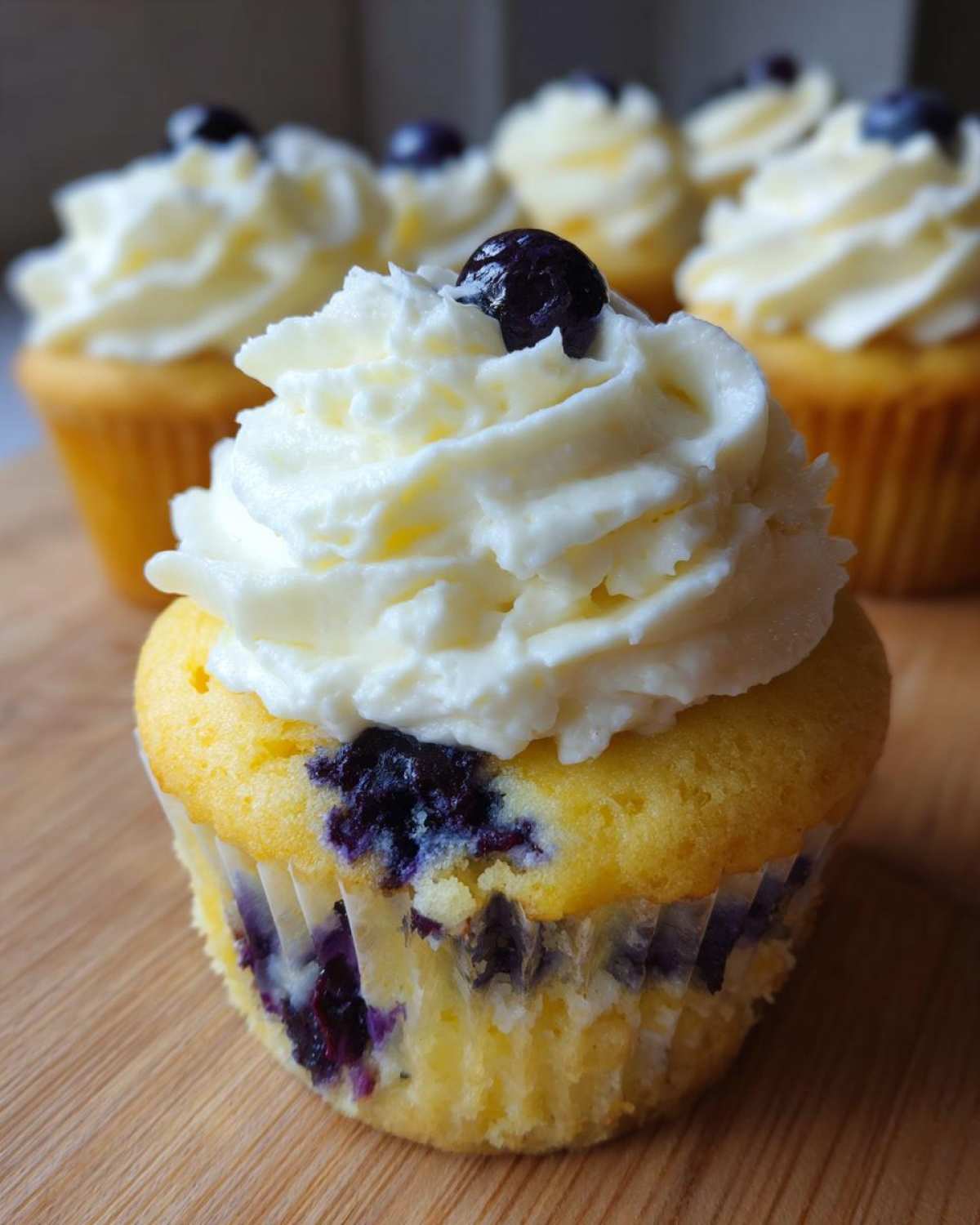 Close-up of a Lemon Blueberry Cupcake with Cream Cheese Frosting topped with a fresh blueberry.