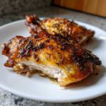Close-up of two perfectly cooked Lemon Garlic Roasted Chicken Thighs with crispy skin and herbs.