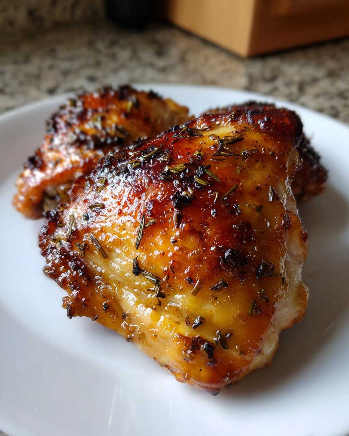 Close-up of perfectly cooked Lemon Garlic Roasted Chicken Thighs with crispy, glazed skin and herbs.