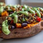 Close-up of a Loaded Veggie Stuffed Sweet Potato topped with quinoa, black beans, and a creamy green sauce.