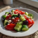 Close-up of a vibrant Mediterranean Cucumber Tomato Salad featuring chunks of tomato, cucumber, feta cheese, and olives.