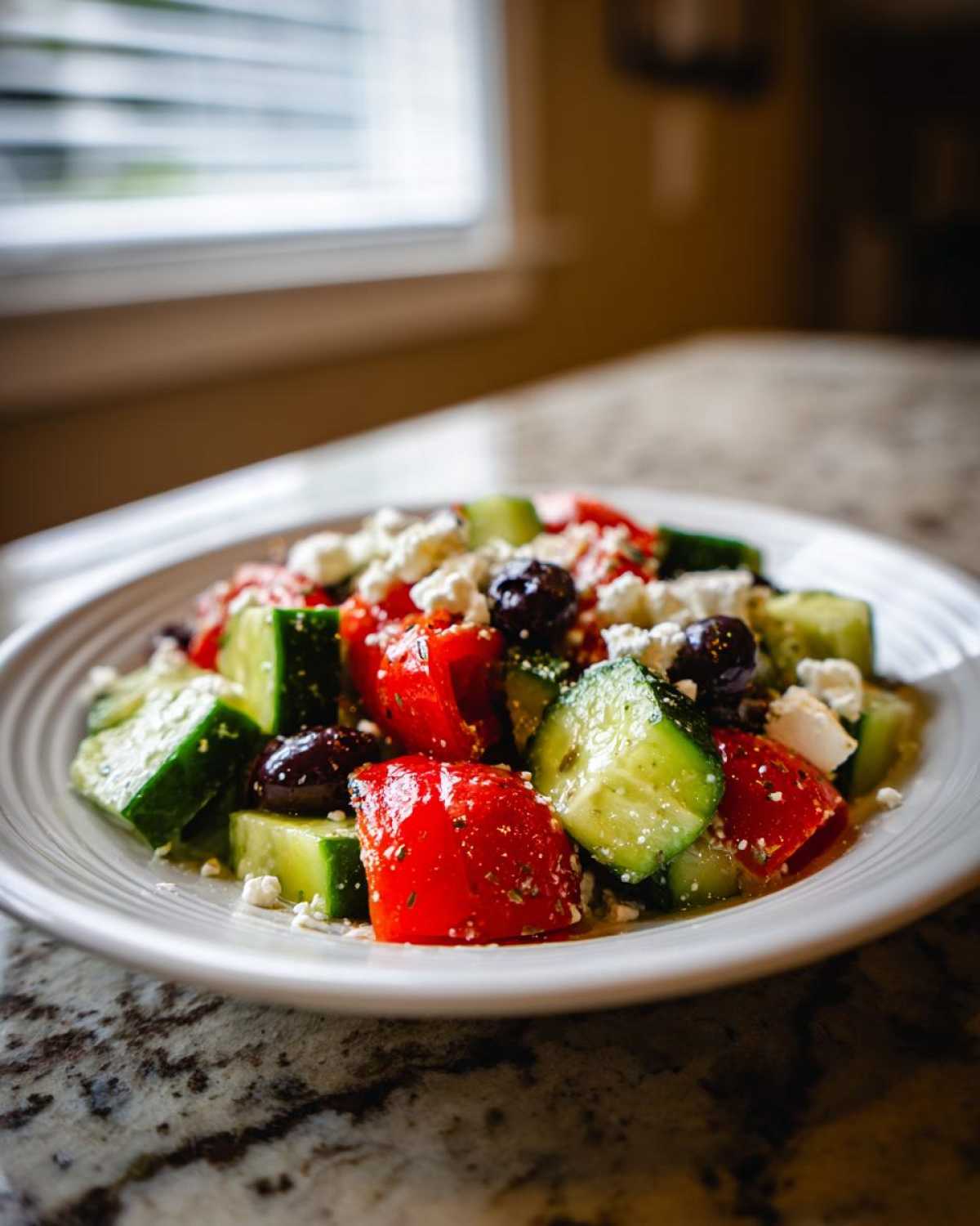 Close-up of a vibrant Mediterranean Cucumber Tomato Salad featuring chunks of cucumber, tomato, olives, and feta cheese.