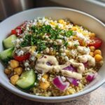 A vibrant Mediterranean Quinoa Bowl topped with feta, chickpeas, cucumber, red onion, and drizzled with lemon tahini sauce.