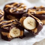 Close-up of No-Bake Chocolate Covered Banana Bites, one cut open revealing a banana slice inside.