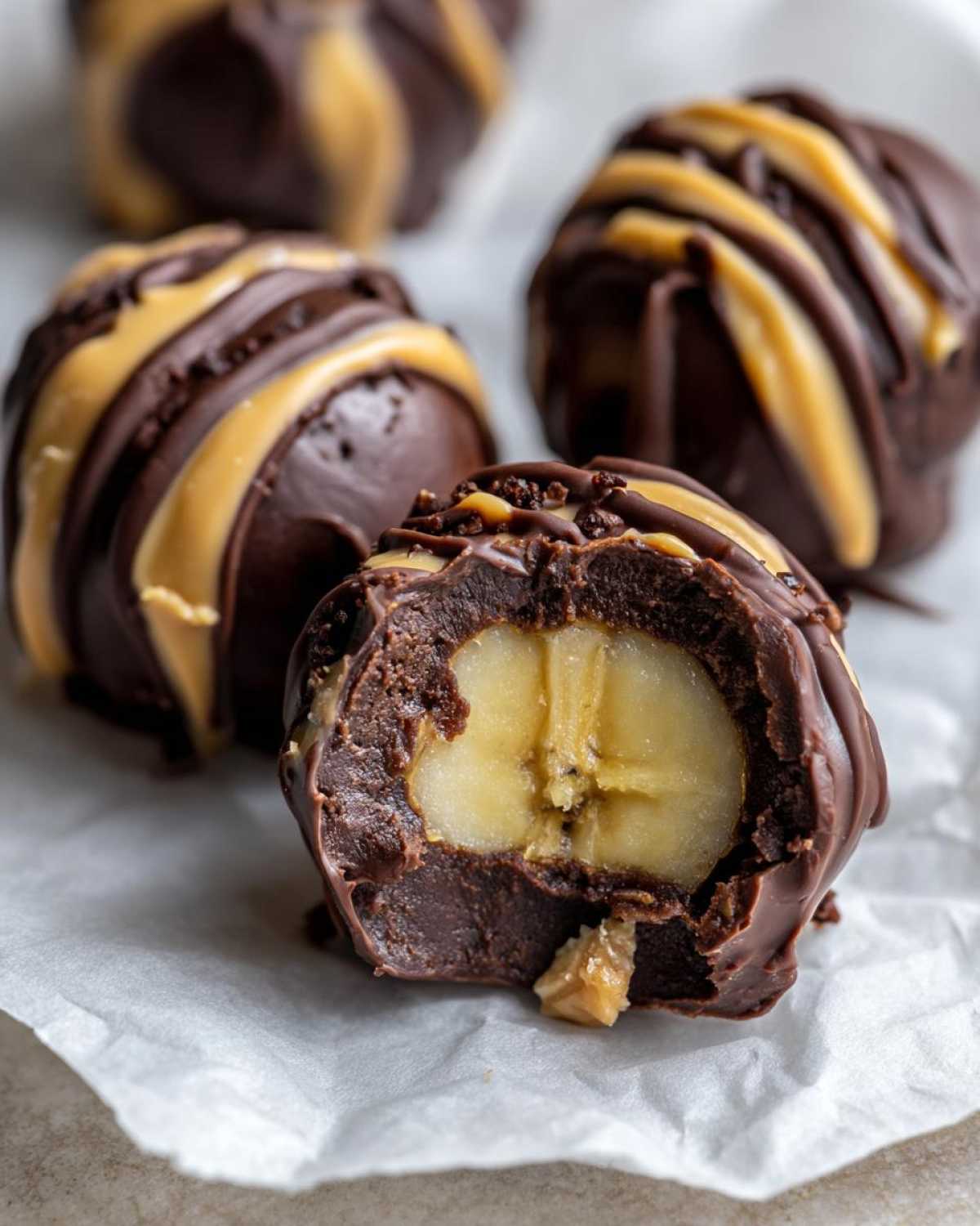 Close-up of a No-Bake Chocolate Covered Banana Bite cut in half showing a banana center surrounded by chocolate fudge.