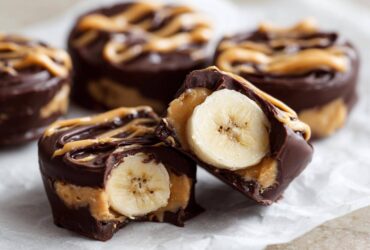 Close-up of No-Bake Chocolate Covered Banana Bites, one cut open revealing a banana slice inside.