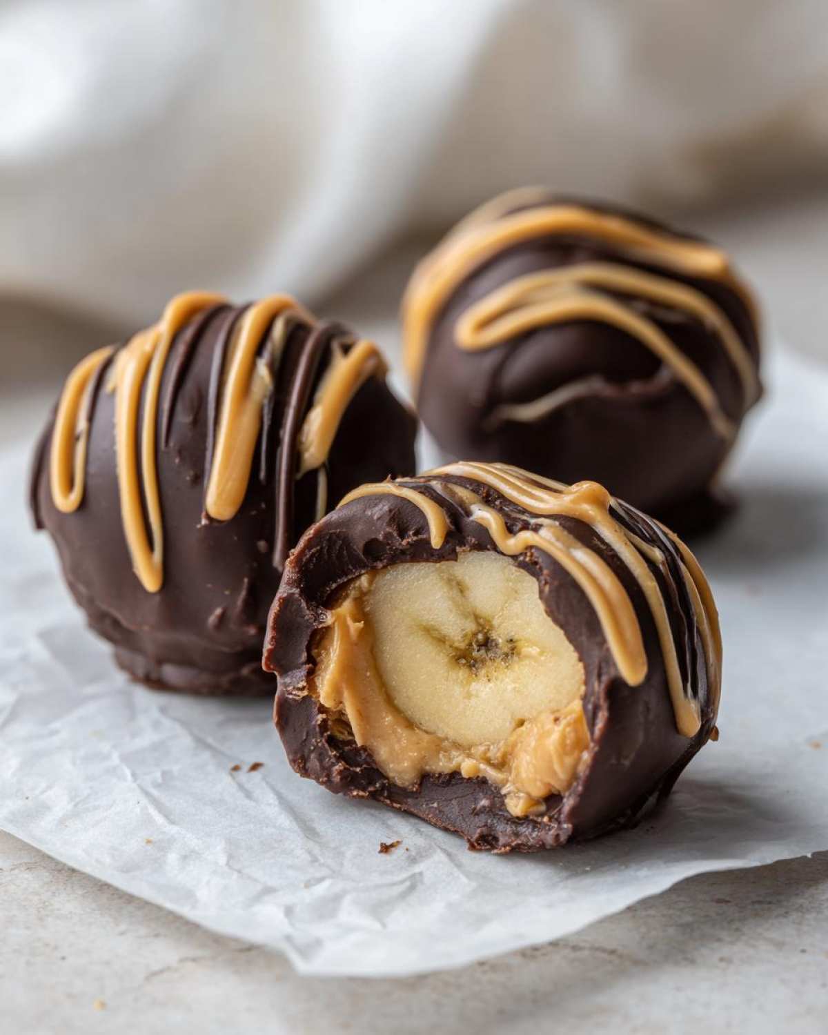 Close-up of a No-Bake Chocolate Covered Banana Bite cut in half, revealing banana and peanut butter filling.