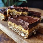 Close-up of delicious No-Bake Chocolate Peanut Butter Oat Bars cut into squares on a wooden board.