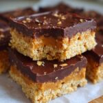 Two stacked No-Bake Chocolate Peanut Butter Oat Bars showing the oat base, peanut butter layer, and chocolate topping.