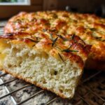 Close-up of a fluffy slice of No-Knead Skillet Focaccia with Rosemary showing the airy crumb and golden crust.