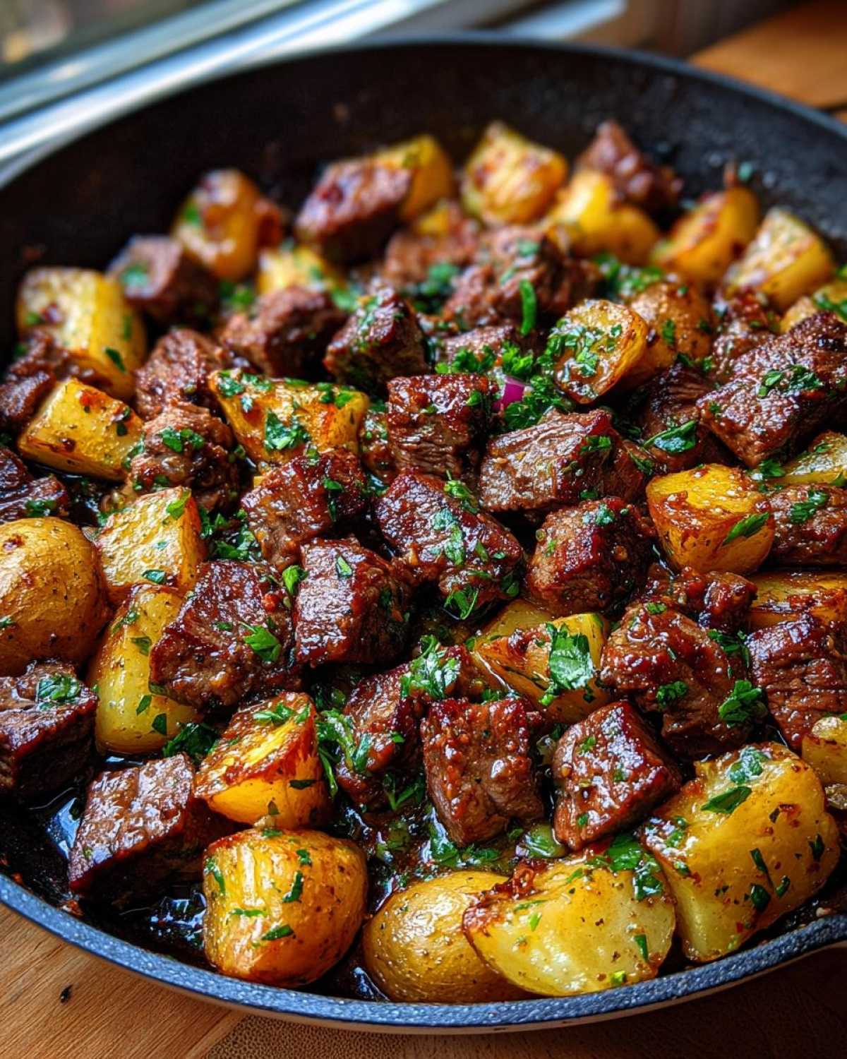 Close-up of juicy, browned One-Pan Garlic Butter Steak Bites mixed with roasted potatoes, garnished with fresh parsley.