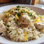 A close-up of One-Pot Chicken and Rice with Lemon and Herbs, topped with fresh parsley and lemon zest.