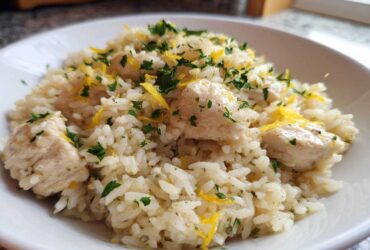 A close-up of One-Pot Chicken and Rice with Lemon and Herbs, topped with fresh parsley and lemon zest.