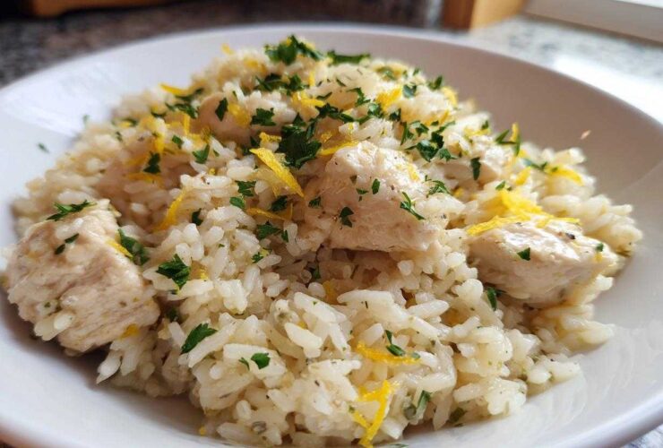 A close-up of One-Pot Chicken and Rice with Lemon and Herbs, topped with fresh parsley and lemon zest.