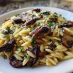 Close-up of a serving of One-Pot Creamy Mushroom Orzo, topped with browned mushrooms and fresh parsley.