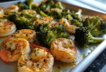 Close-up of cooked shrimp and broccoli florets seasoned with garlic butter on a sheet pan.