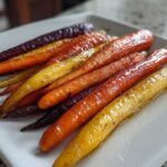 Close-up of glistening Sheet Pan Roasted Rainbow Carrots with Honey on a white platter.