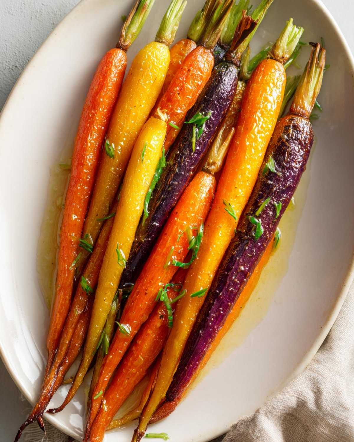 Close-up of glossy Sheet Pan Roasted Rainbow Carrots with Honey, garnished with fresh herbs.